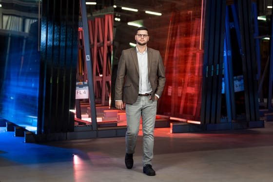 Verslo portretas gamybos erdvėje, žmogus eina link kameros