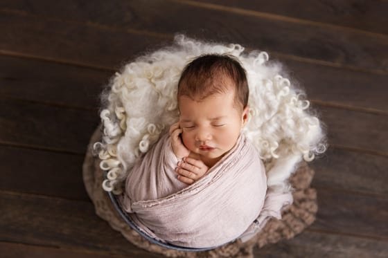 Wrapped newborn in a fur-lined bowl — after retouching