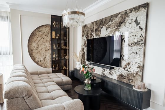 Svetainė su akmens plokšte ties televizoriumi ir minkšta sofa