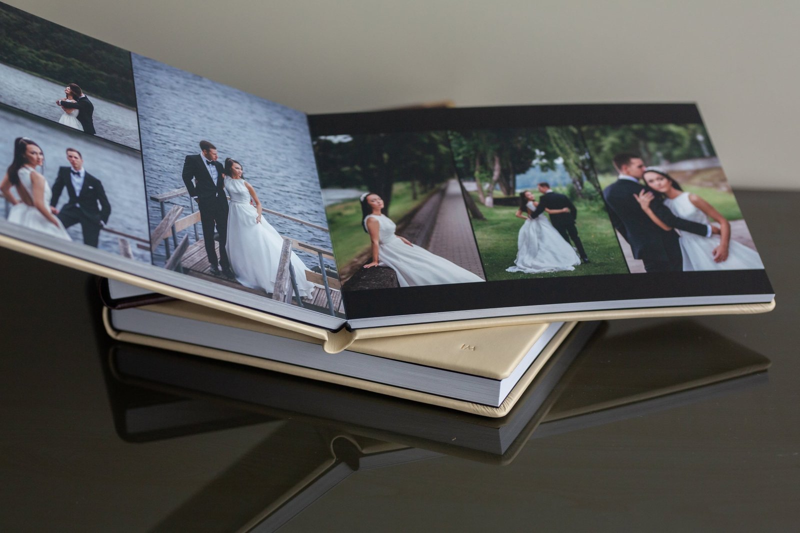 Atversta vestuvių fotoknyga, padėta ant kitos knygos kreminiu viršeliu