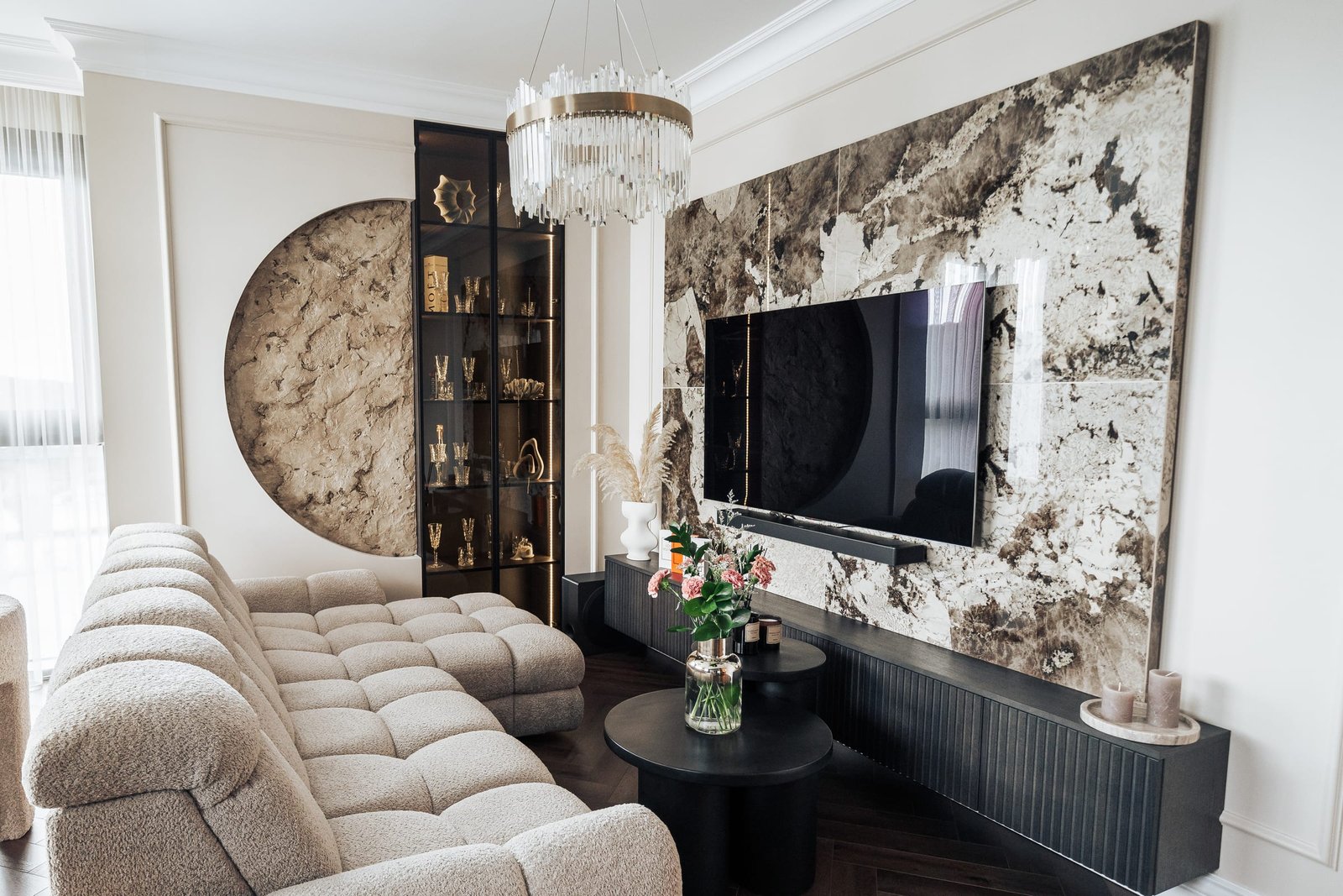 Svetainė su šviesia minkšta sofa, marmuro siena ir televizoriumi